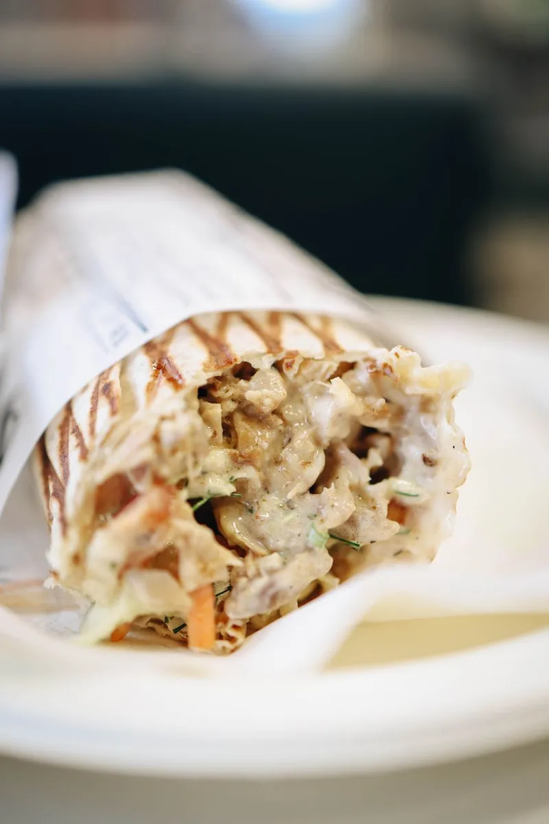 Close-up of a delicious grilled chicken shawarma wrap on a plate, perfect for food lovers.